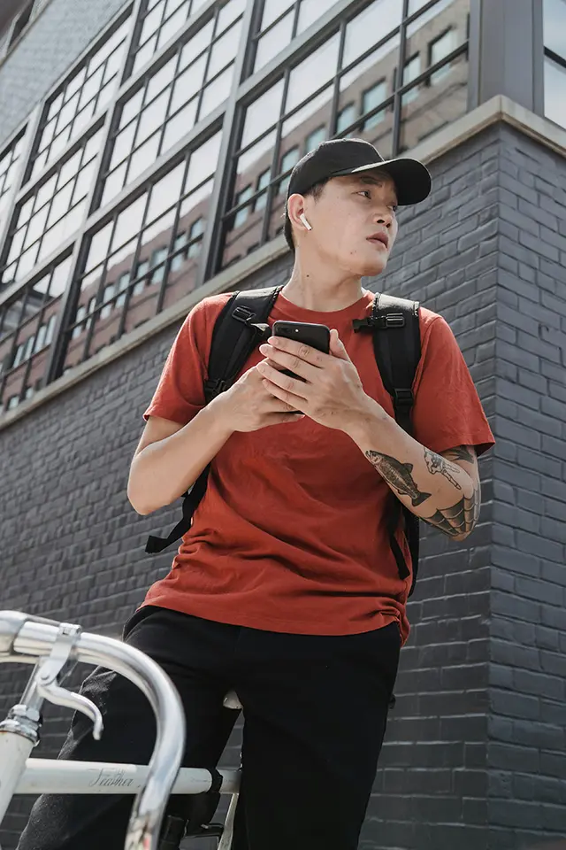 A young man looks around anxiously, phone in hand.