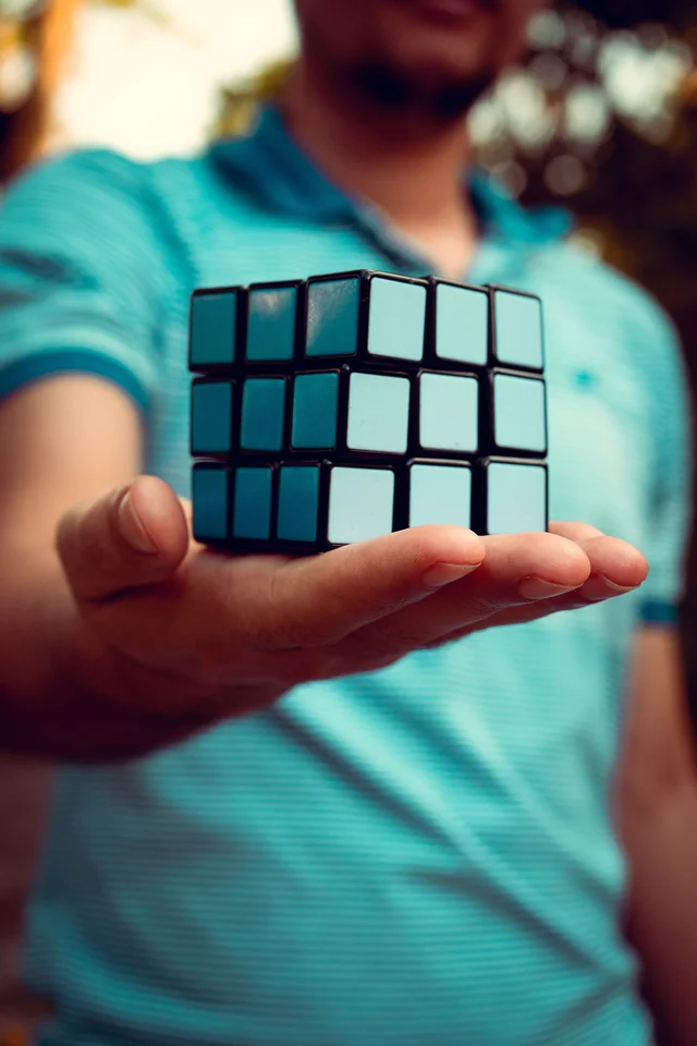 An entirely light blue Rubik's cube, held out on an open palm, solved.